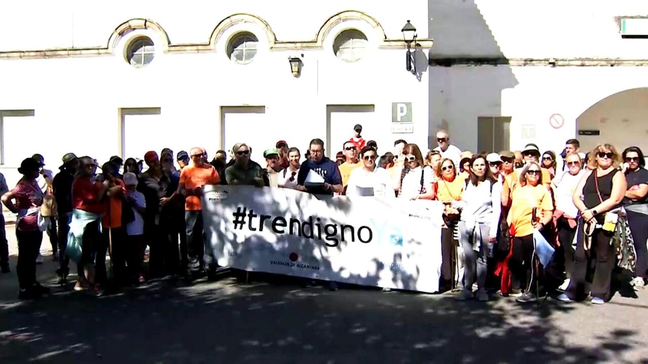 Grupo de personas posa tras una pancarta con el lema #trendigno
