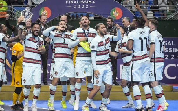 Jugadores con uniforme de Portugal celebran juntos bajo un cartel de Finalíssima 2022