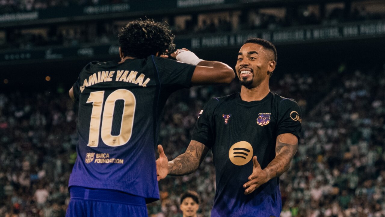 Lamine Yamal, de espaldas, y Gabriel Jesus celebran juntos sobre el césped.