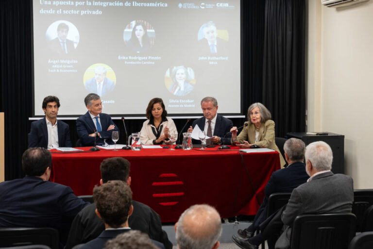 Cinco participantes en una mesa de debate frente al público durante una jornada iberoamericana.