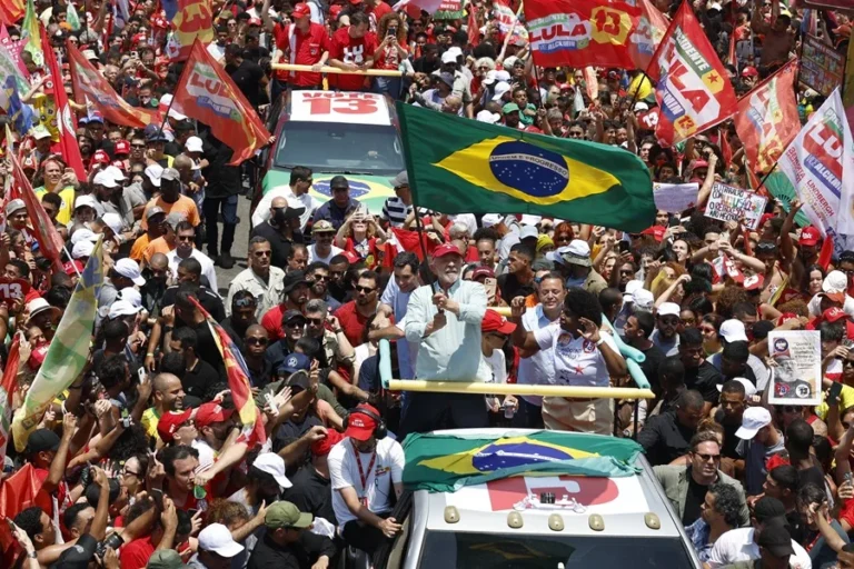 Multitud rodea un vehículo mientras ondean banderas de Brasil y de Lula