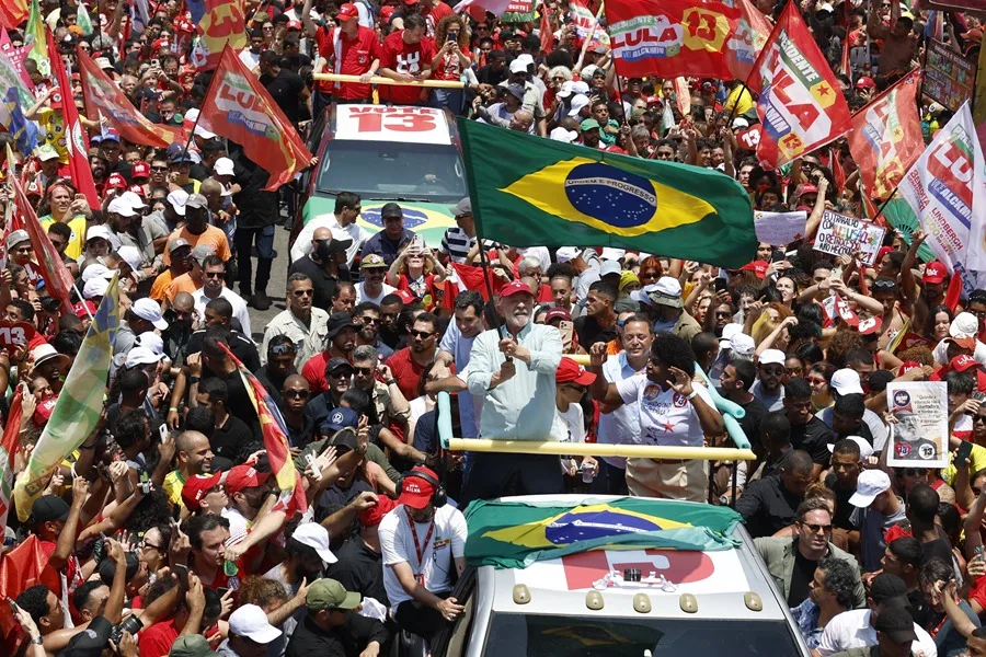 Multitud rodea un vehículo mientras ondean banderas de Brasil y de Lula