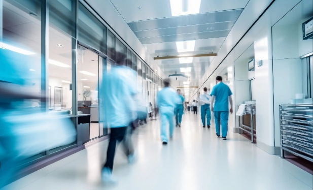 Personas con ropa azul en un pasillo hospitalario amplio y luminoso