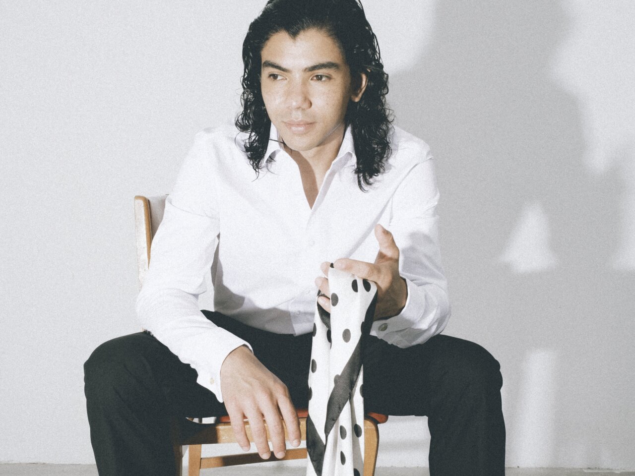 Hombre sentado con camisa blanca sostiene una tela blanca con manchas negras