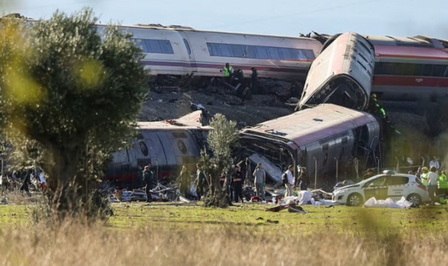 Varios trenes descarrilados junto a personas con chalecos de alta visibilidad en una zona rural